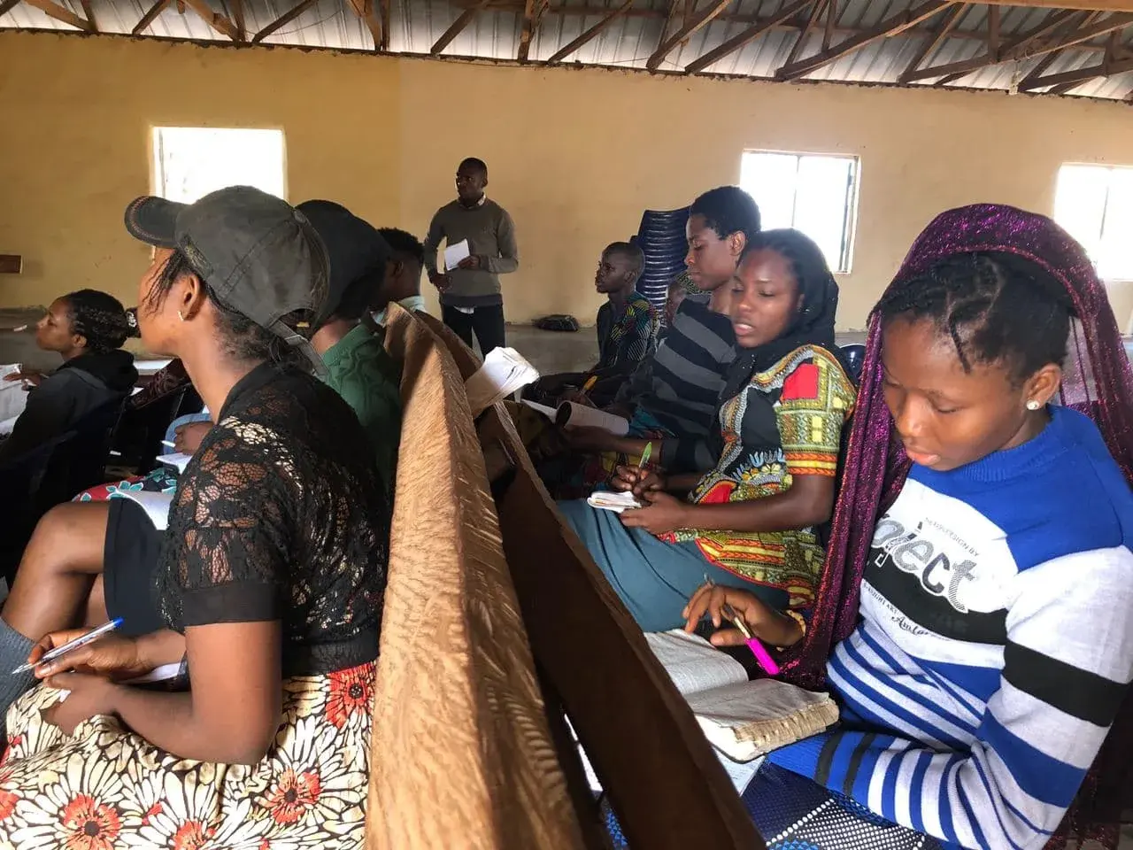 Participants with notebooks studying together in a hall