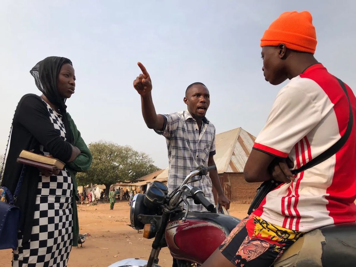 A team member sharing the gospel with a man on a motorcycle and a woman holding a Bible