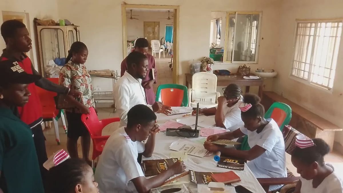 Team members sharing Bibles and literature with people seated at a table
