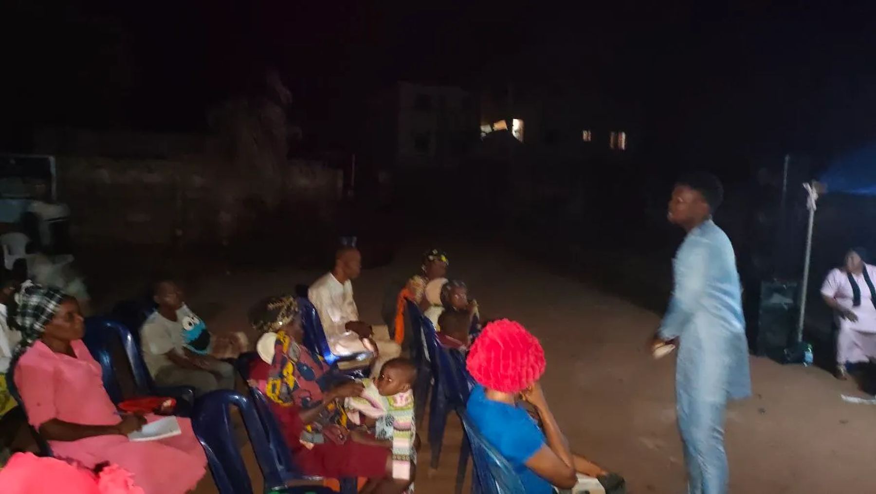 A team member speaking to people seated at the night meeting
