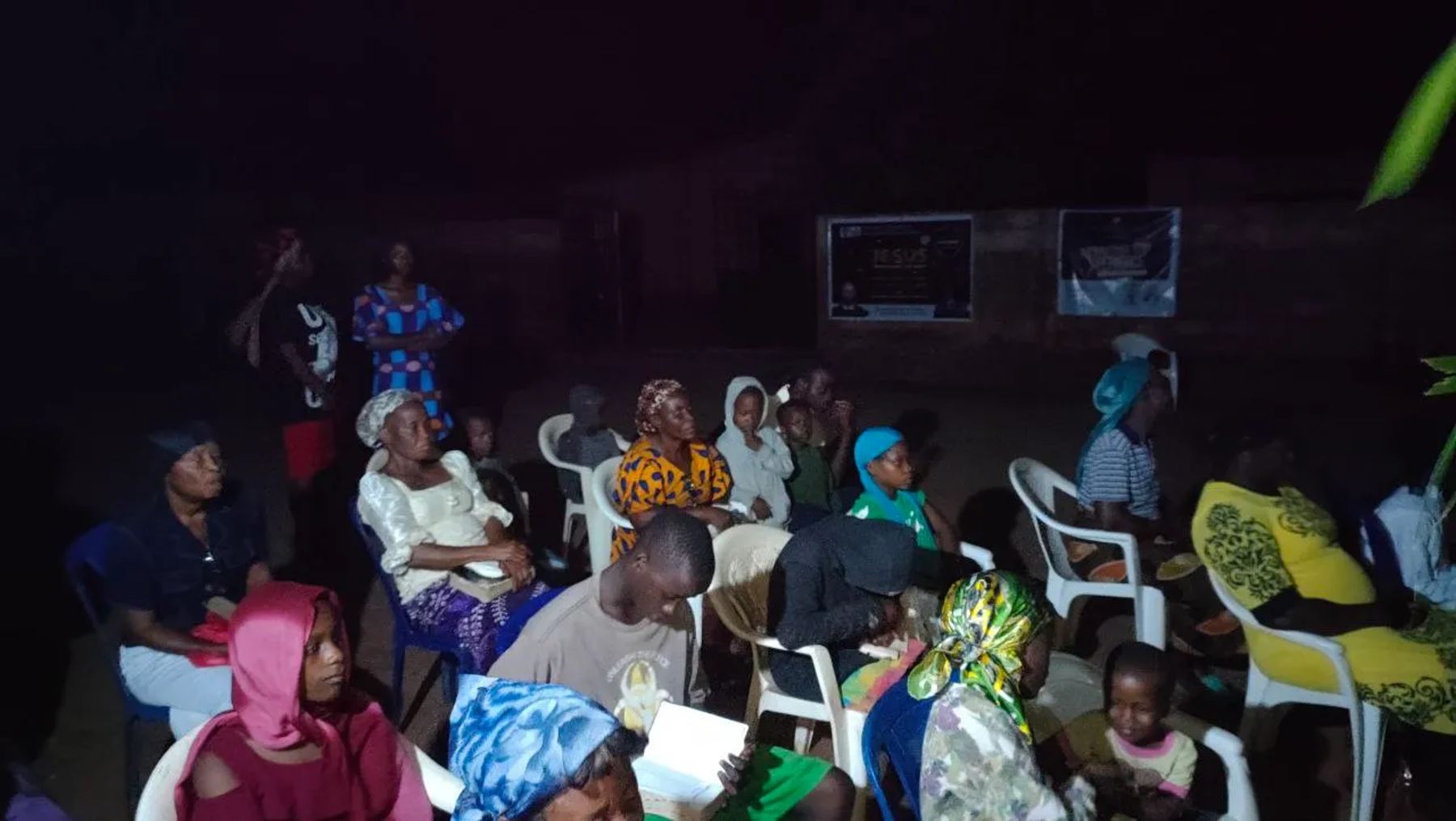 People seated at the night meeting, some holding Bibles