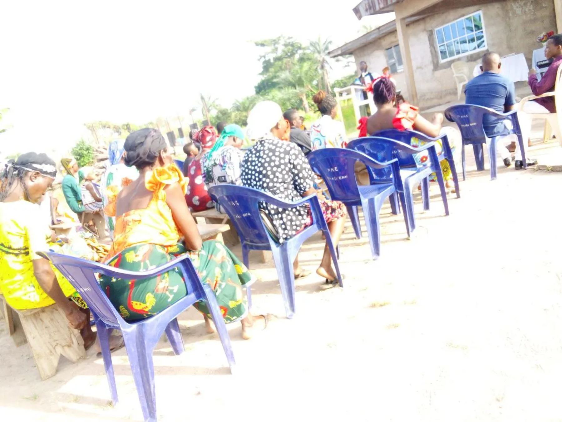 People seated on blue chairs at a daytime meeting