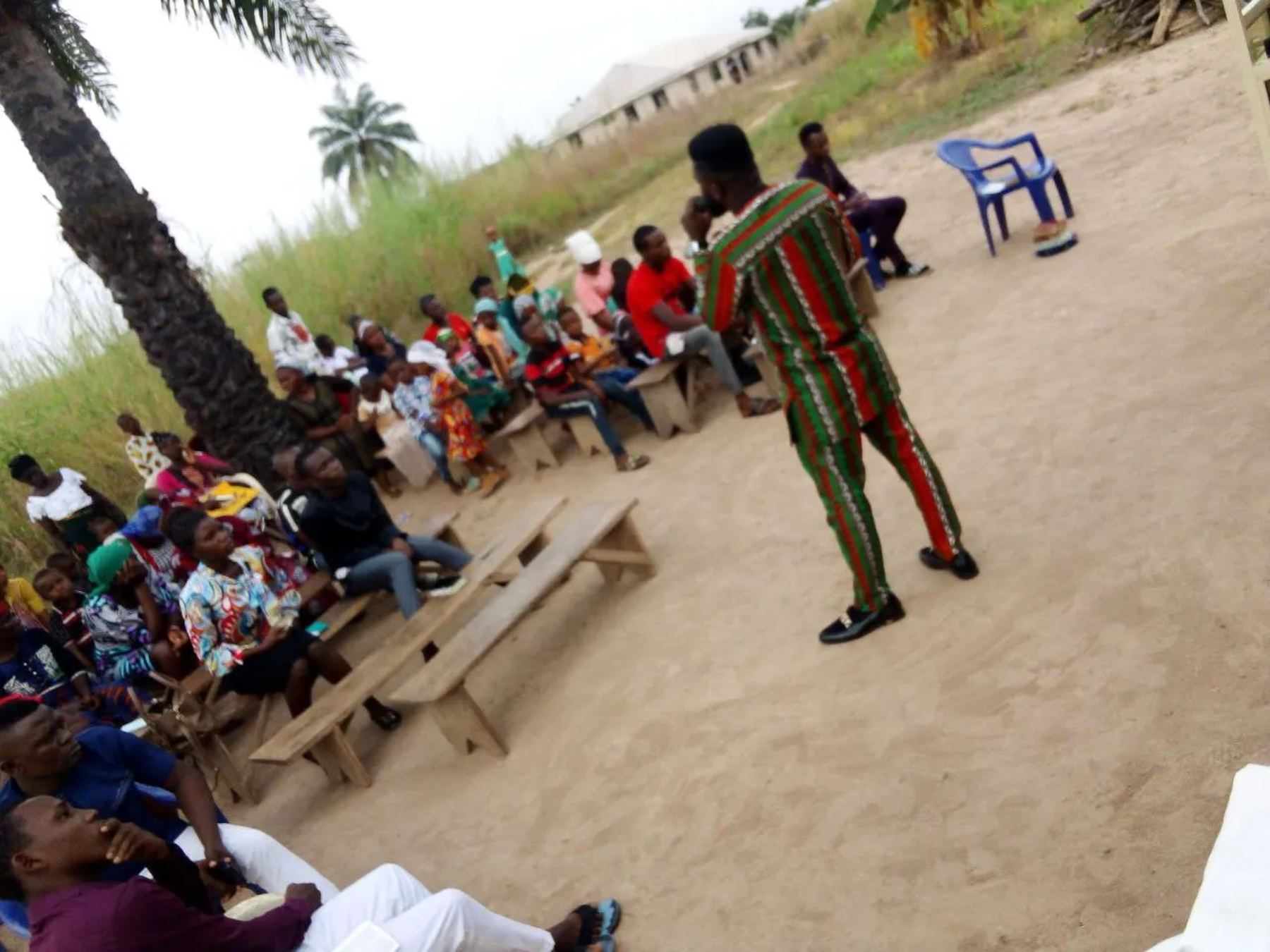 A preacher addressing people seated on benches outdoors