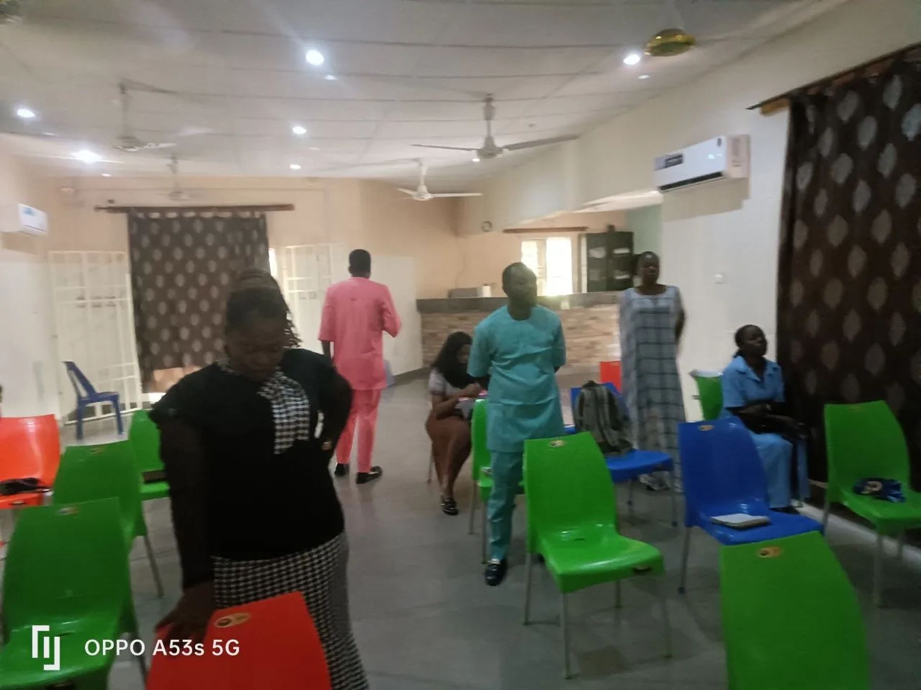 Participants arriving and taking seats on red, green and blue chairs in the conference hall