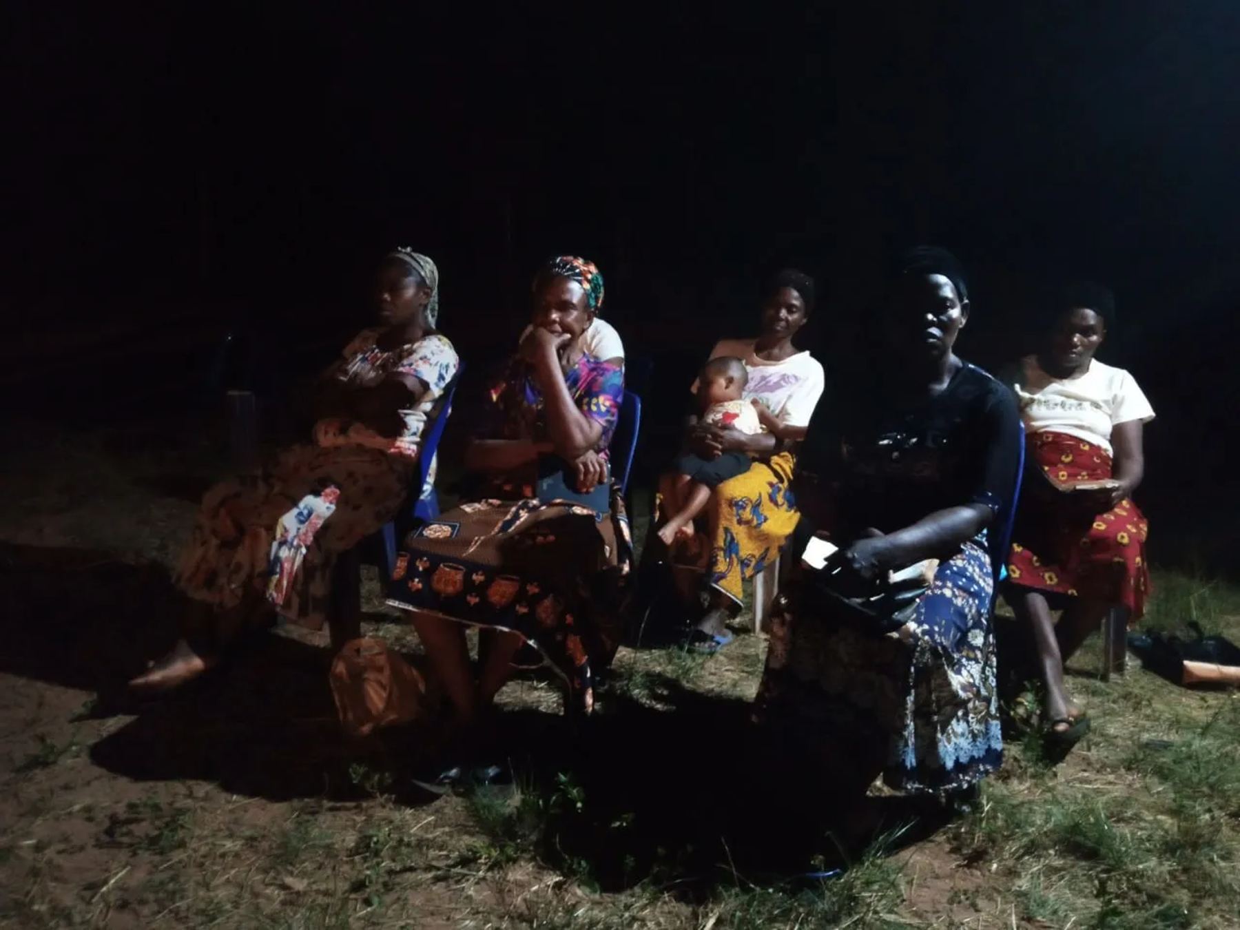 Women seated on the grass at the night meeting