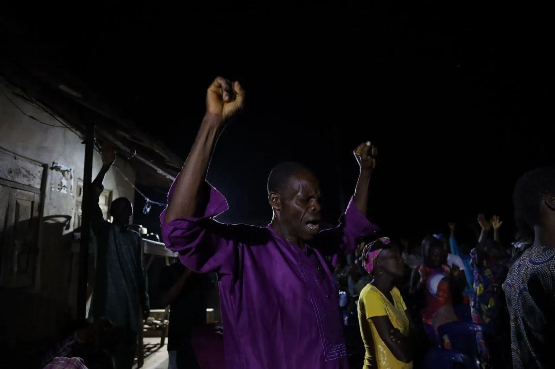 A man with fists raised in worship at the night crusade