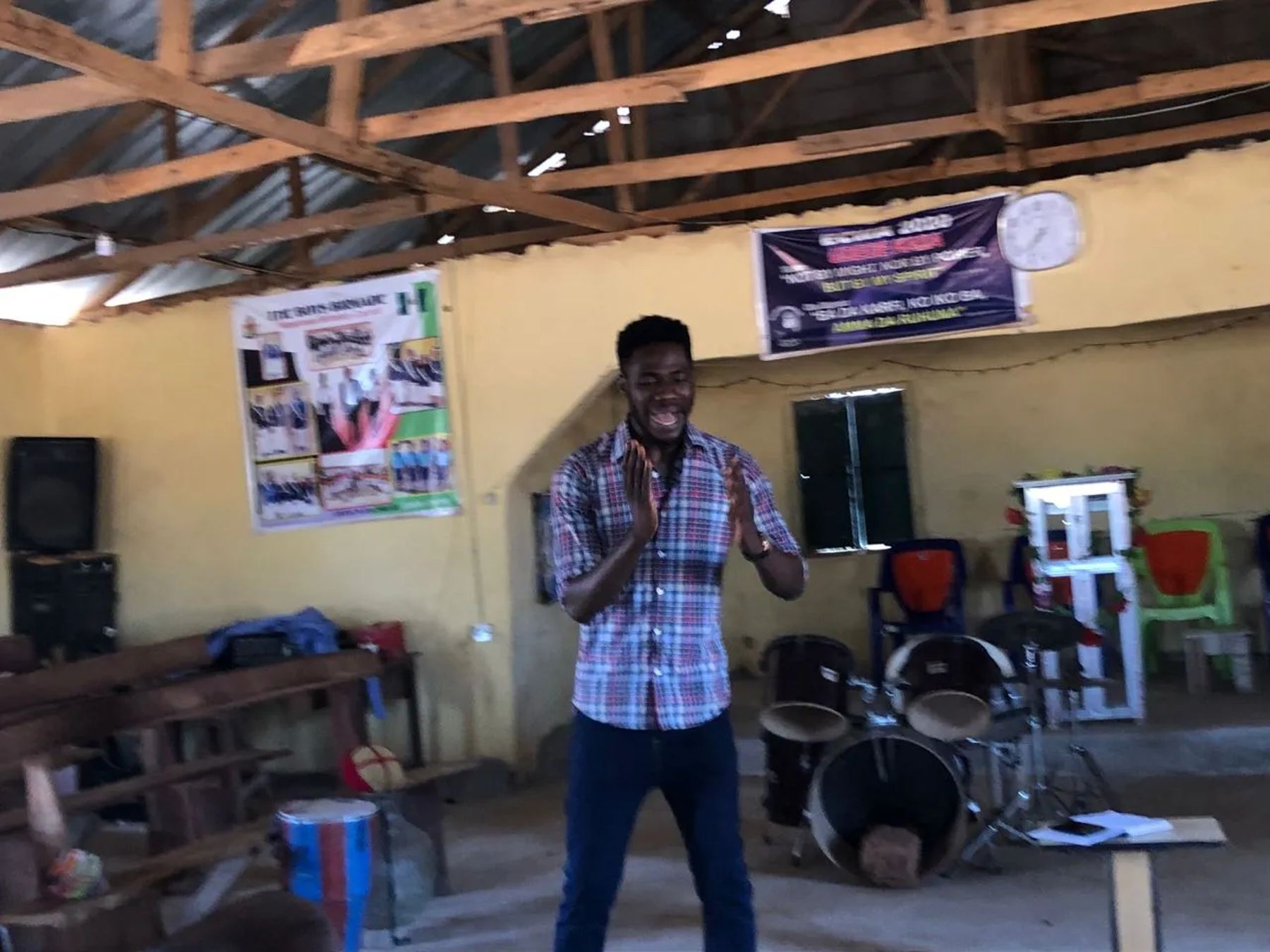 A team member speaking inside the hall, with drums behind