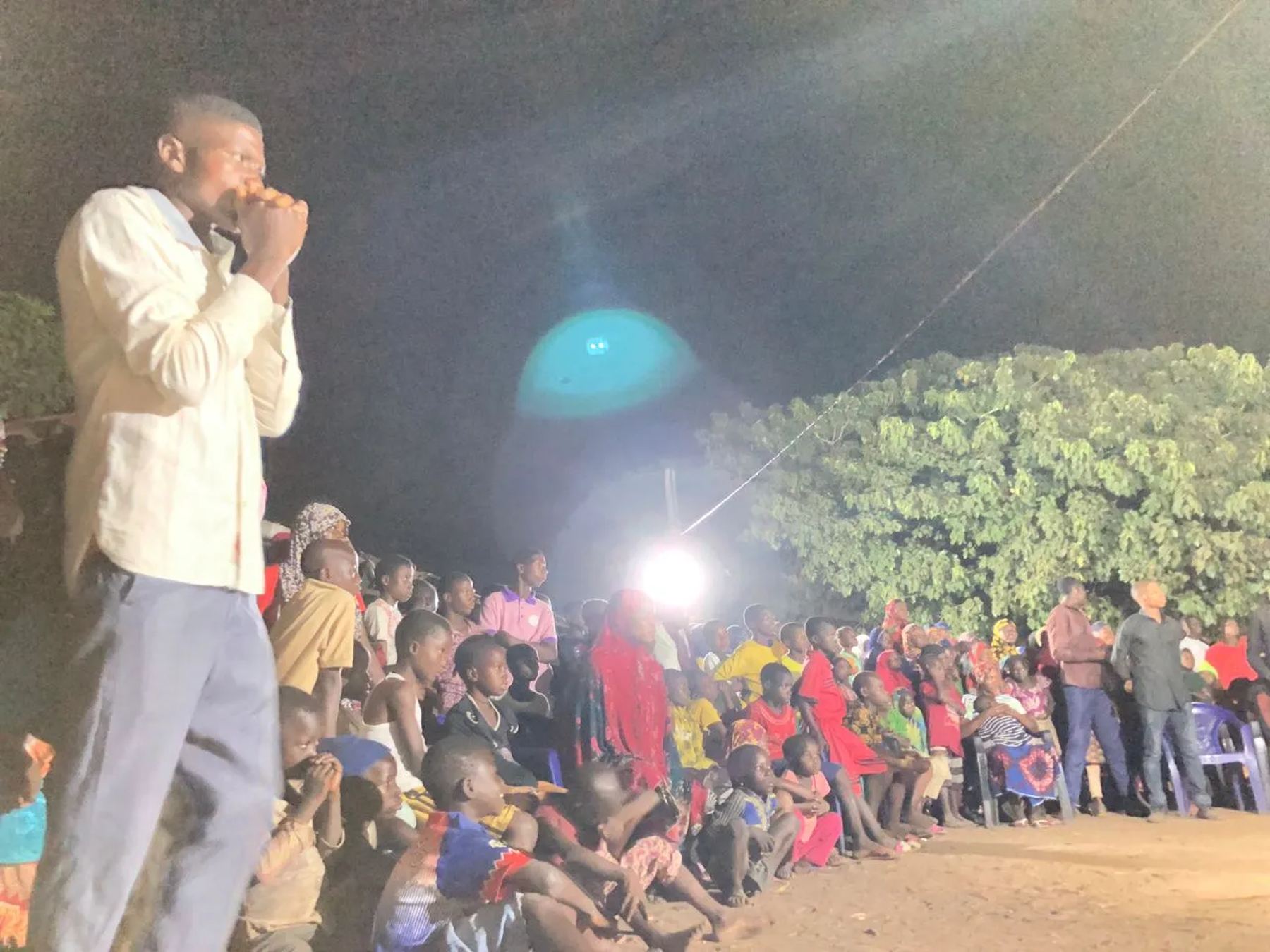A team member speaking to a large crowd at night