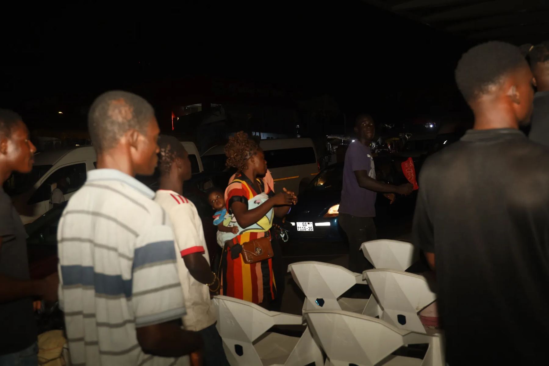 People gathering among white plastic chairs at the evening outreach
