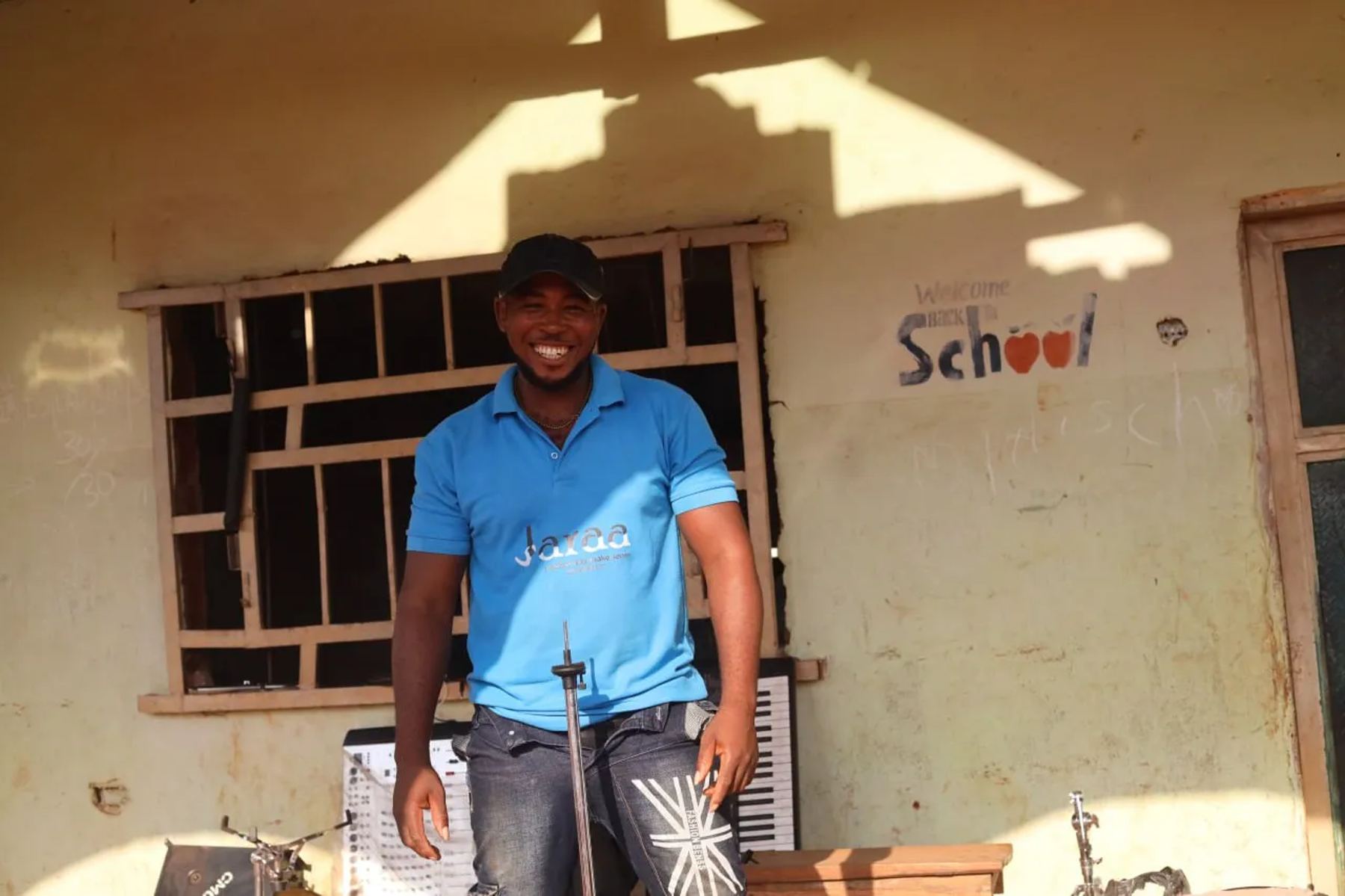 A team member in a blue T-shirt outside a school building