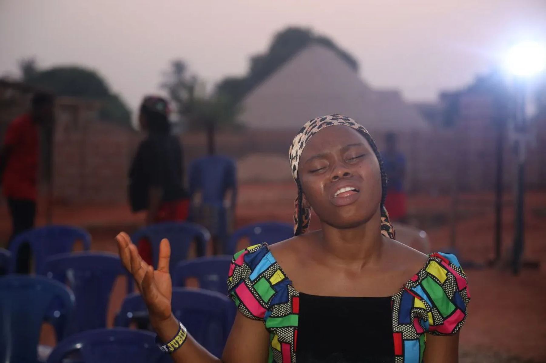 A young woman praying with an outstretched hand at dusk