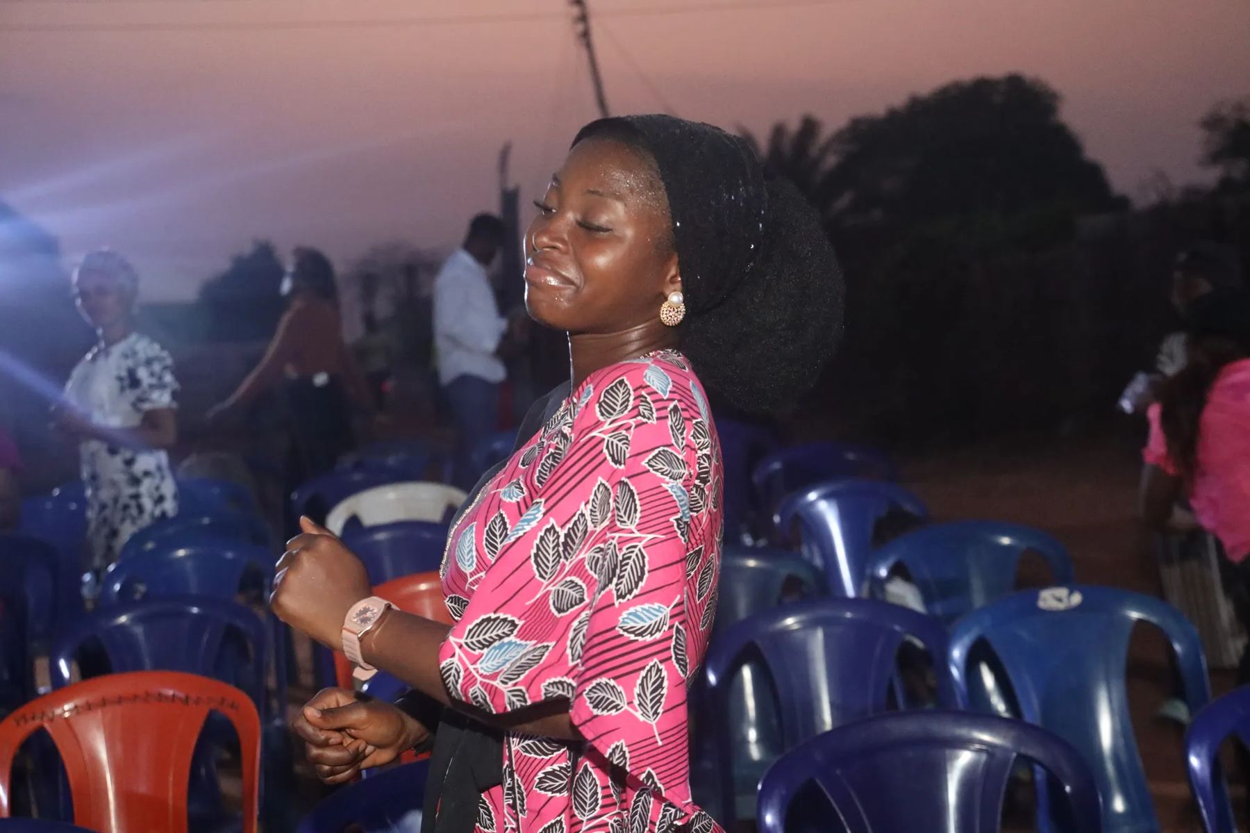 A woman worshipping among the chairs at dusk