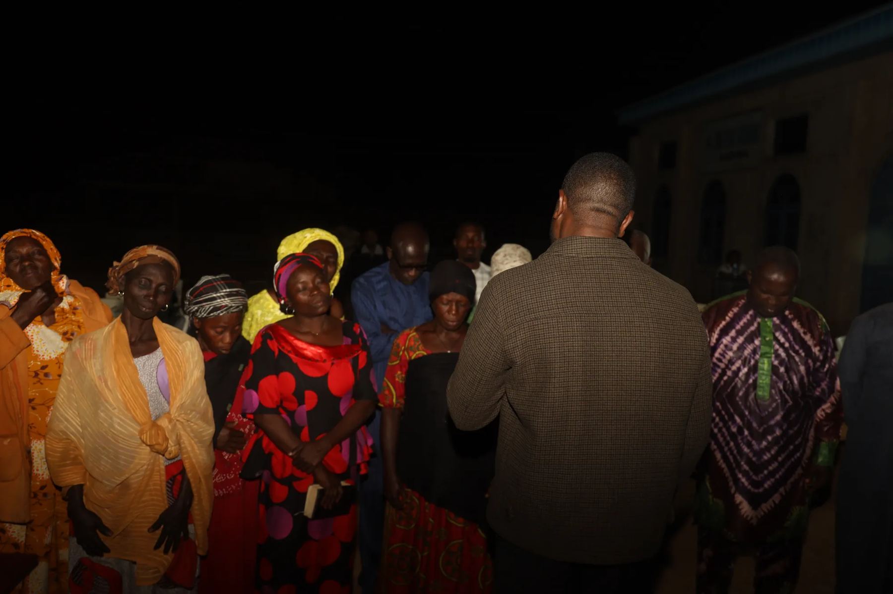 Women in head scarves gathered at night with a team member