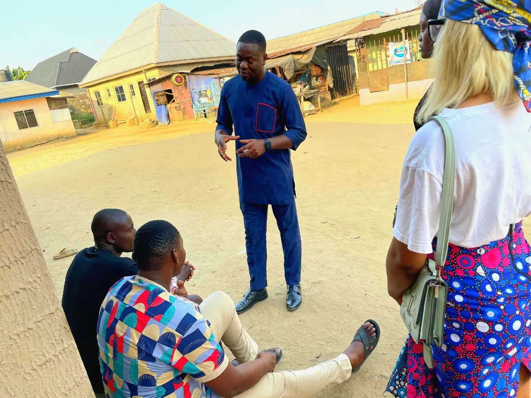 A team member talking with men seated by the roadside