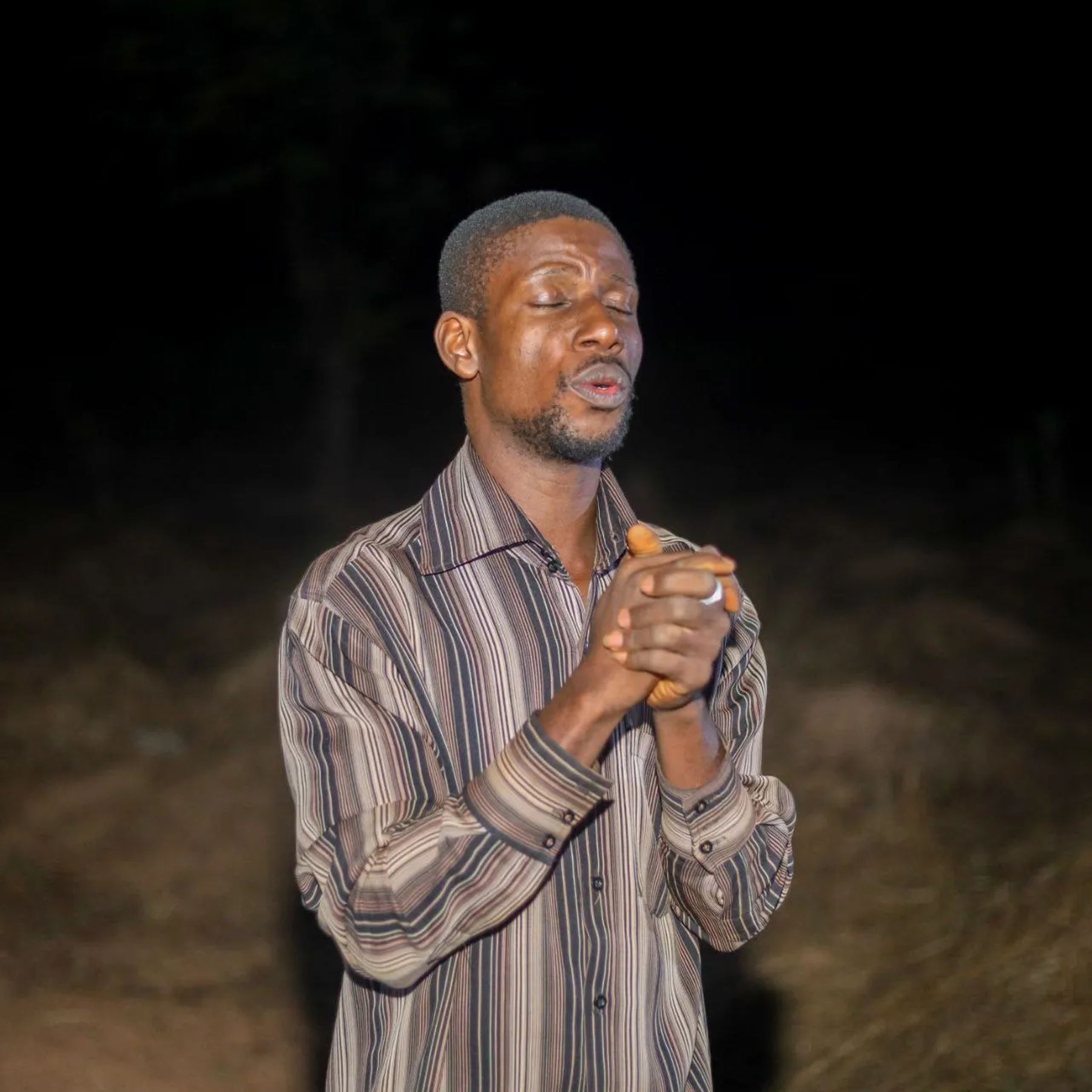 A man praying with clasped hands at night