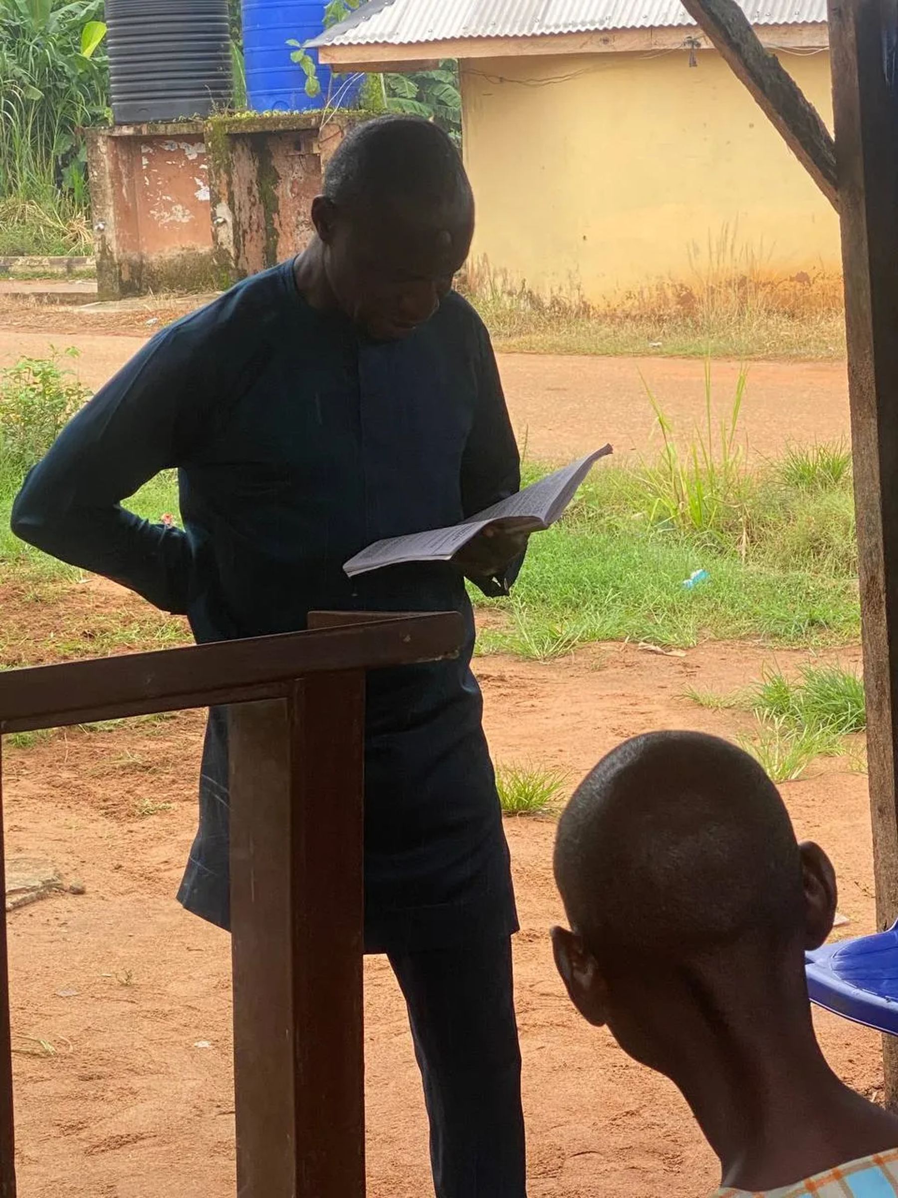 A man reading from the Bible at a wooden lectern outdoors