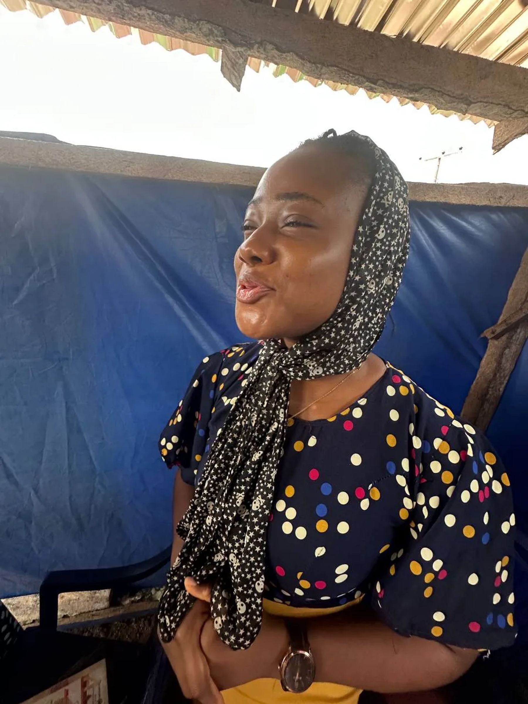 A woman speaking under the blue canopy