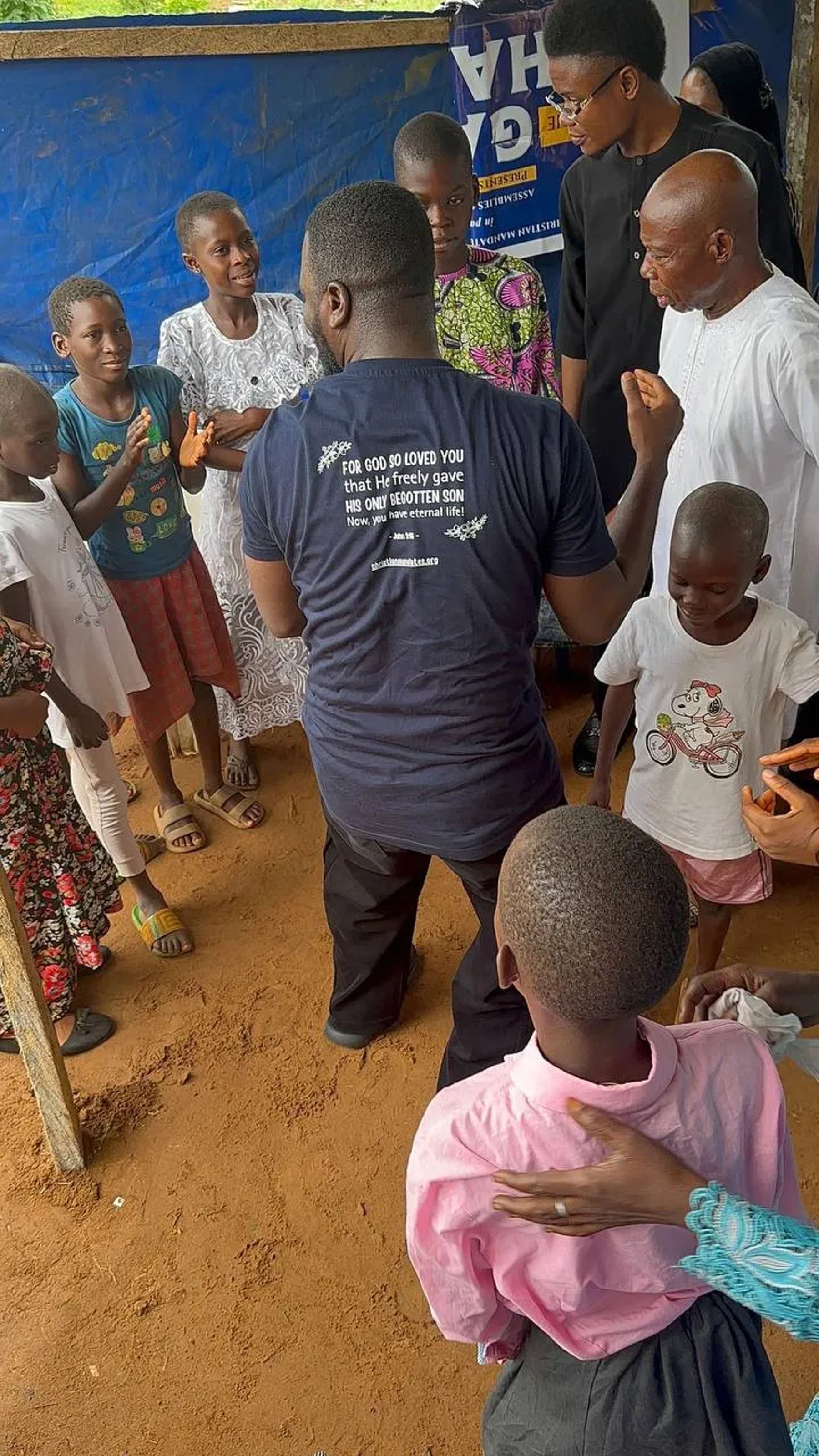 A team member talking with children under the canopy
