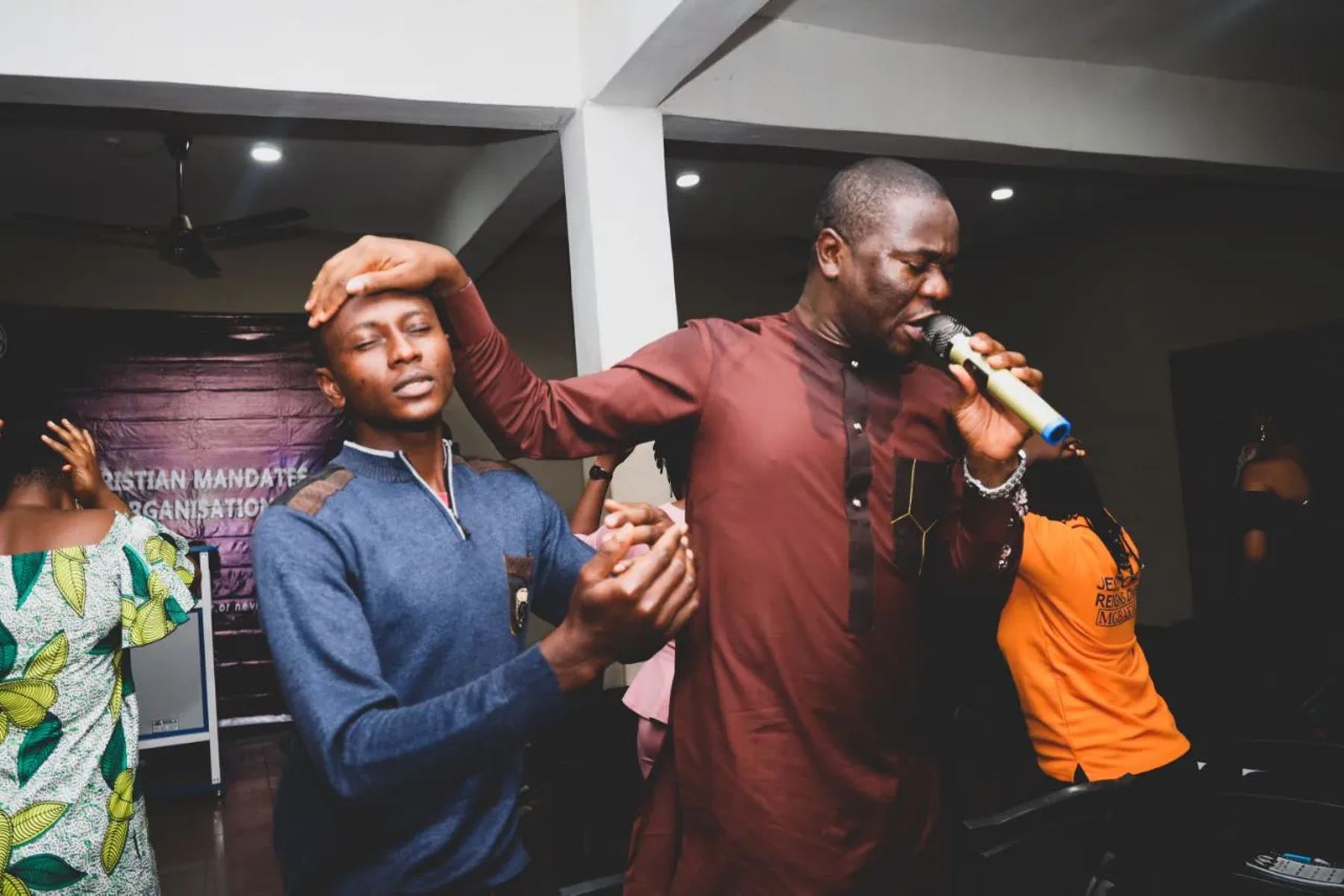The minister praying for a young man, his hand on his head