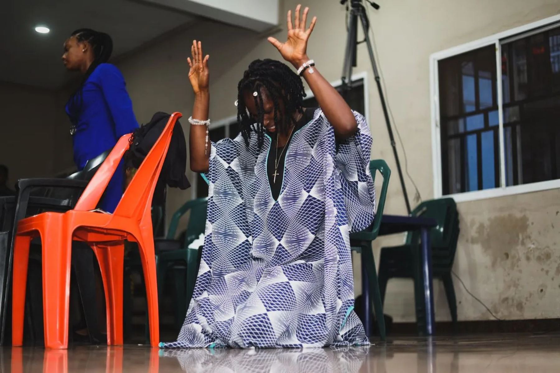 A woman kneeling with hands raised in prayer