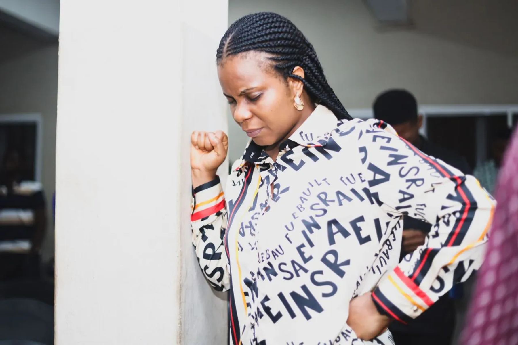 A woman praying against a wall