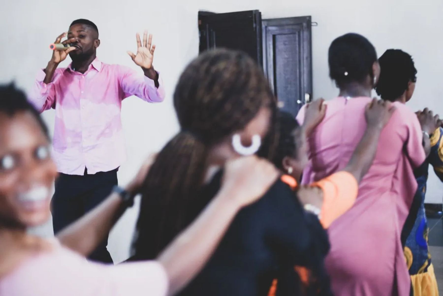 A man leading prayer as participants pray with hands on one another's shoulders