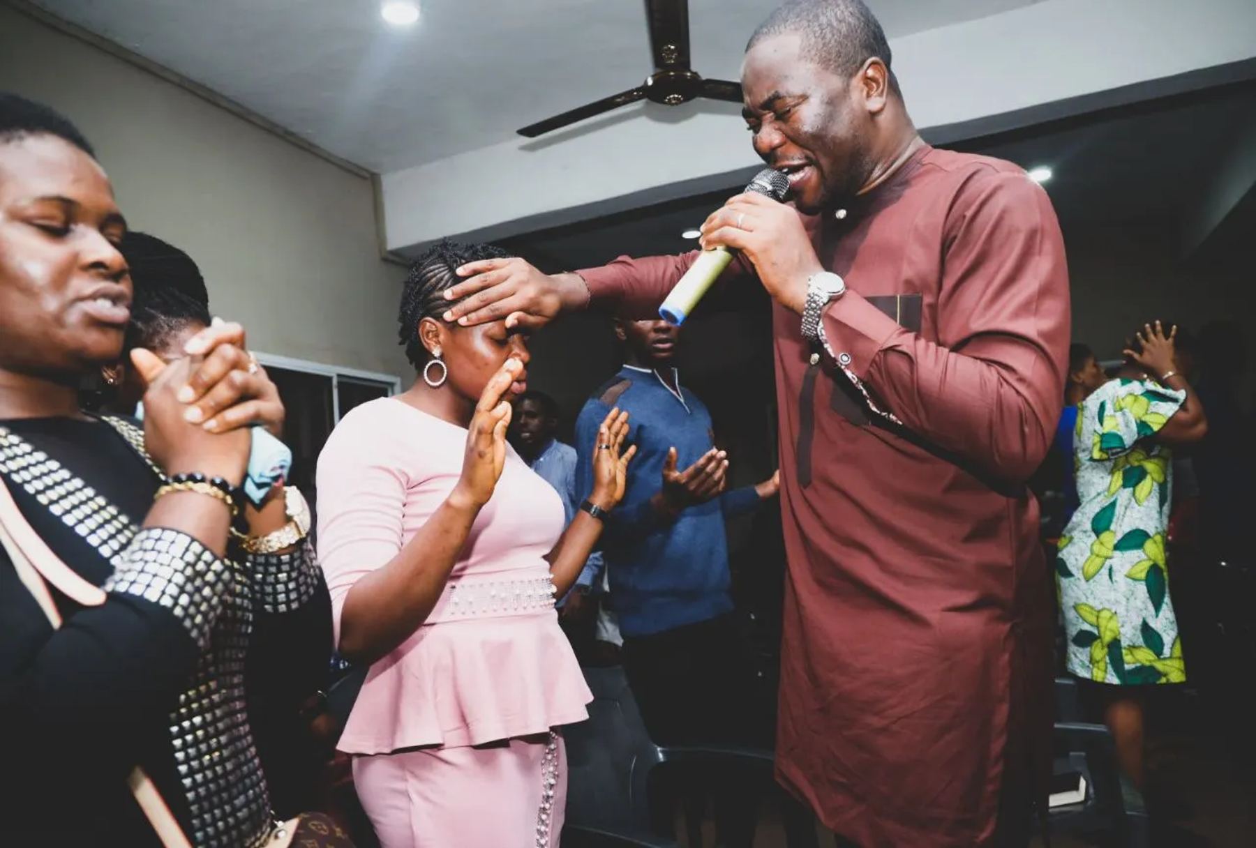 The minister praying for a participant, his hand on her forehead