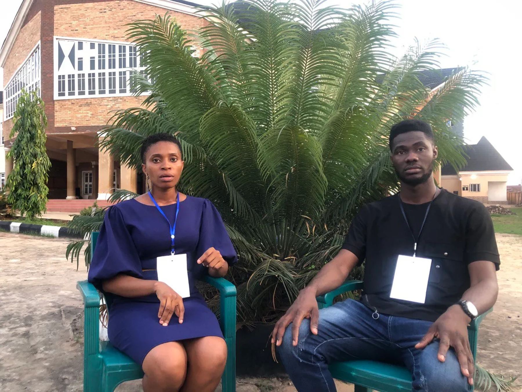 Two participants seated outdoors in front of palms