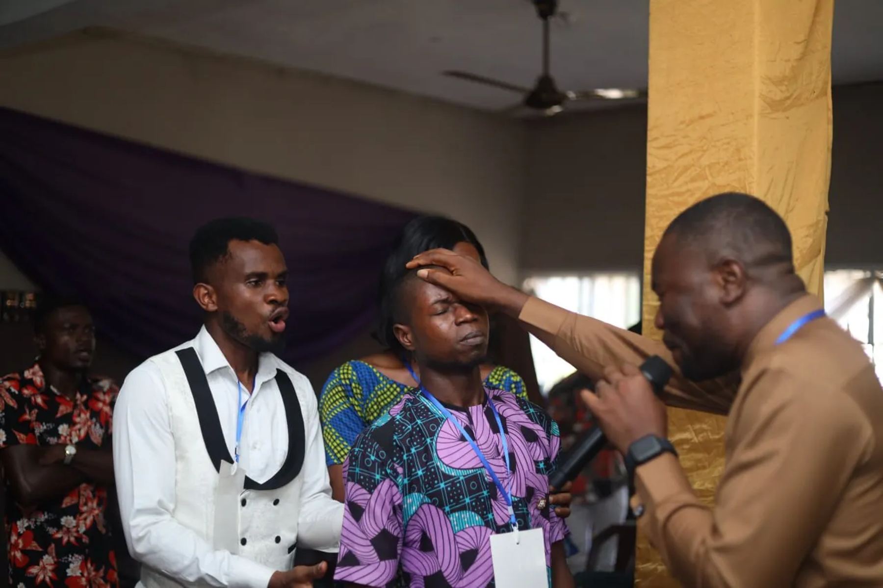 A minister praying for a participant, his hand on her forehead