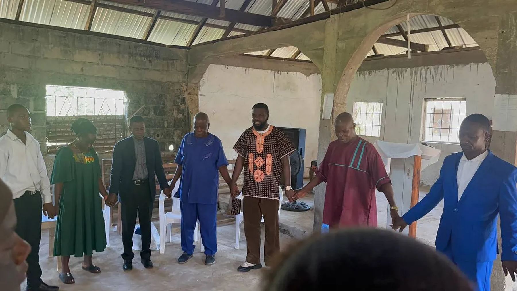 Church leaders and team members holding hands in a prayer circle
