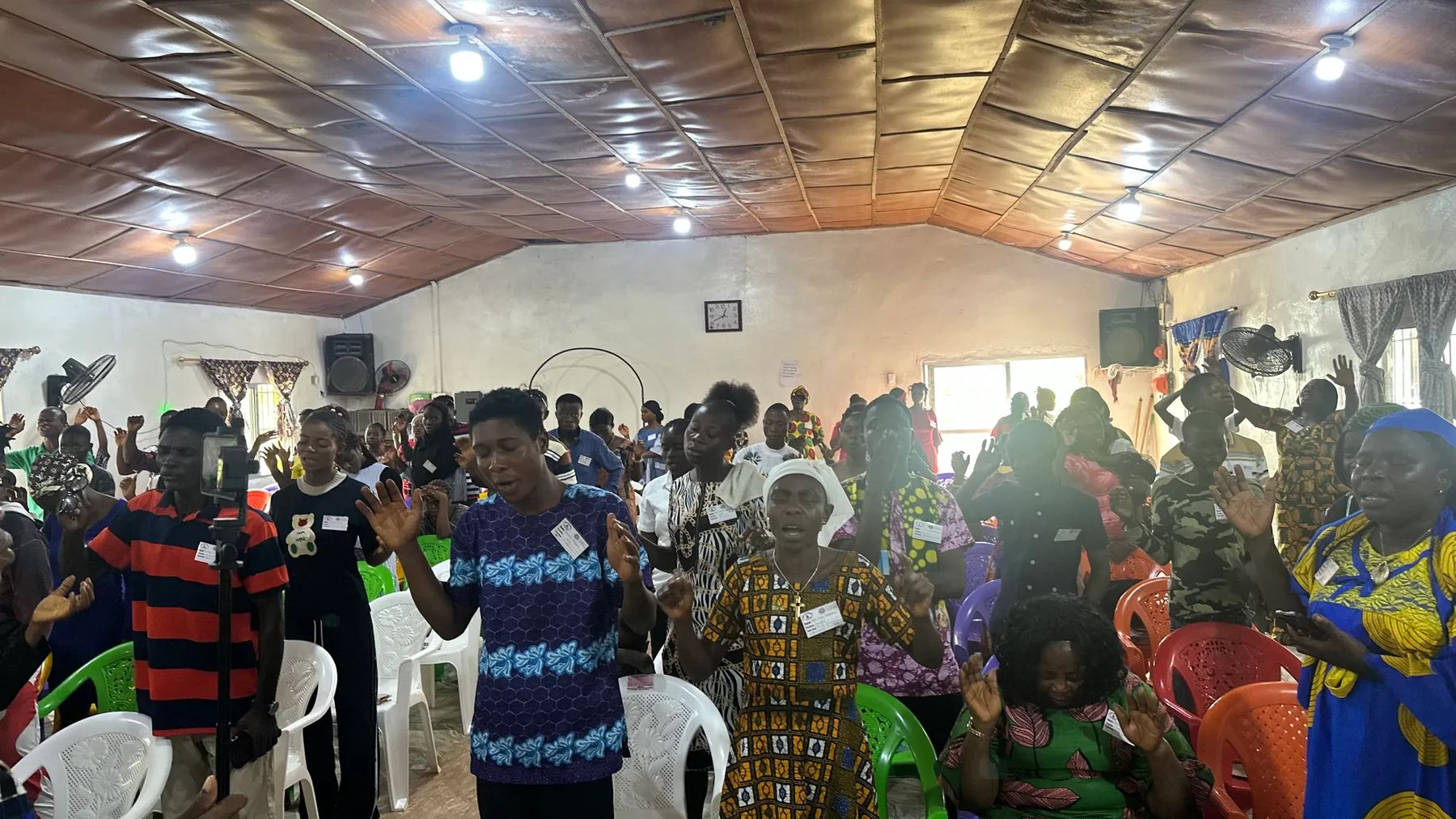 The congregation standing with hands raised in worship