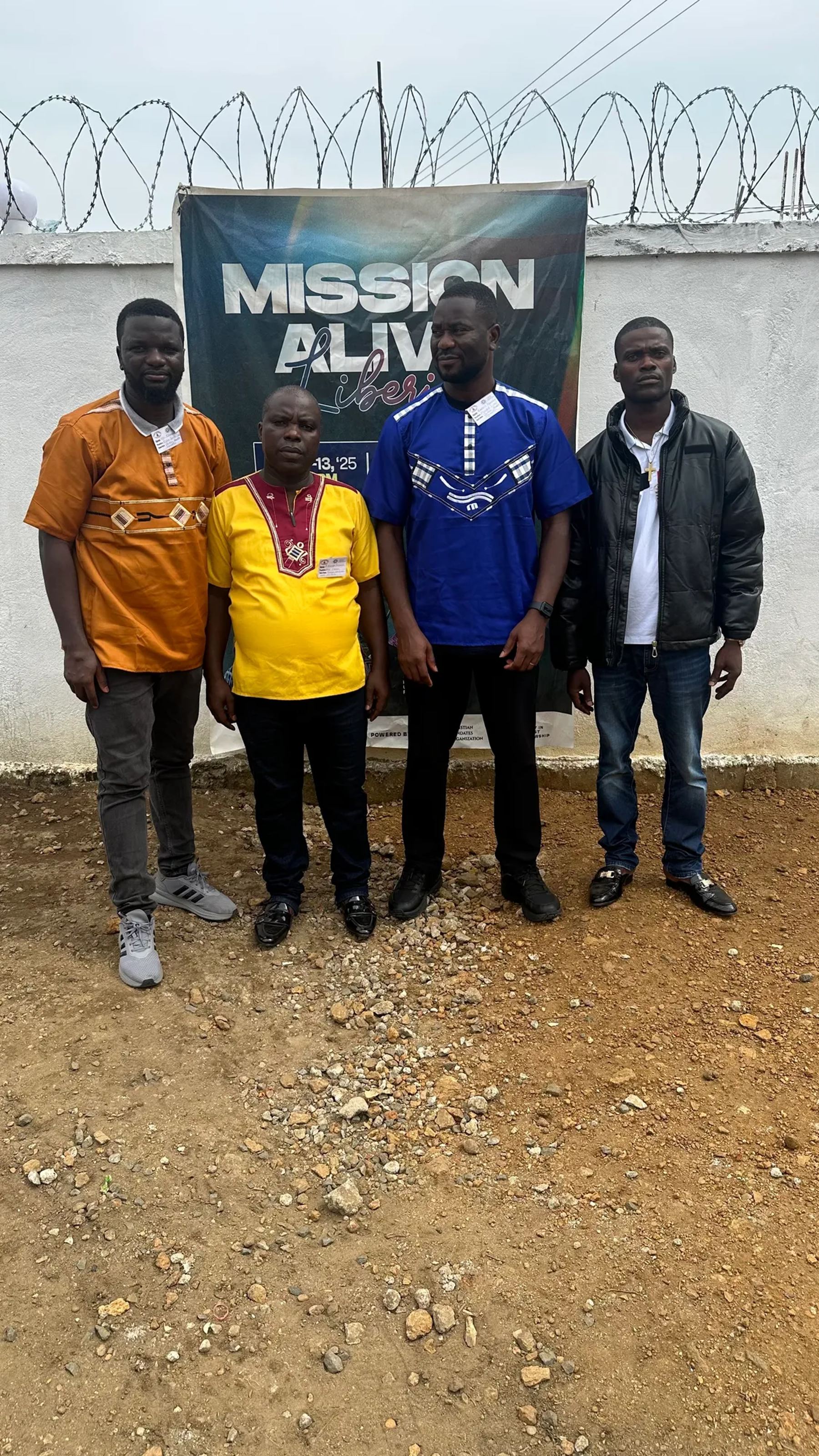 Four team members standing in front of a Mission Alive banner outside