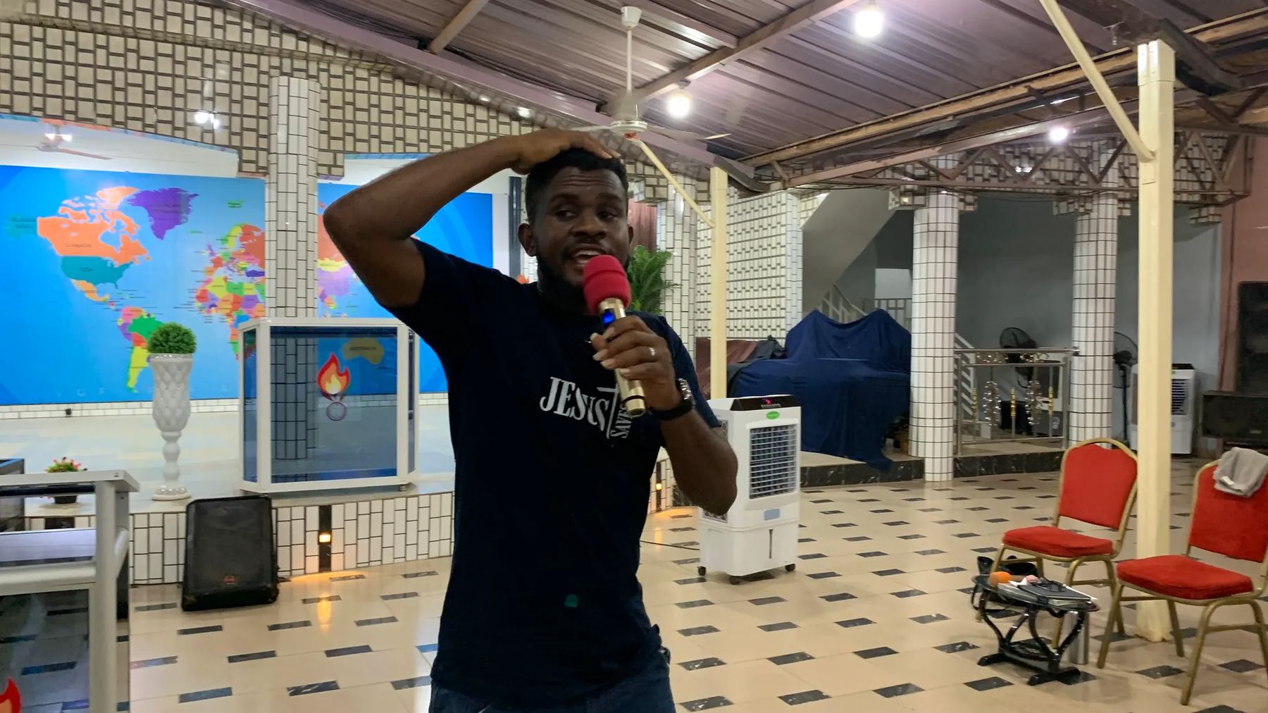 A team member in a Jesus T-shirt preaching with a microphone