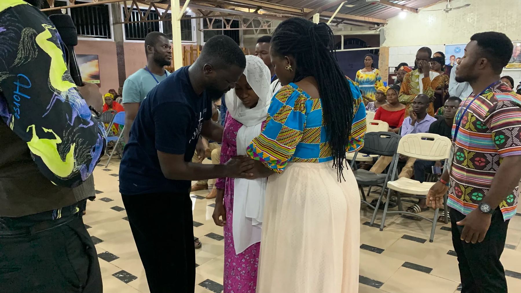 A team member praying with two women