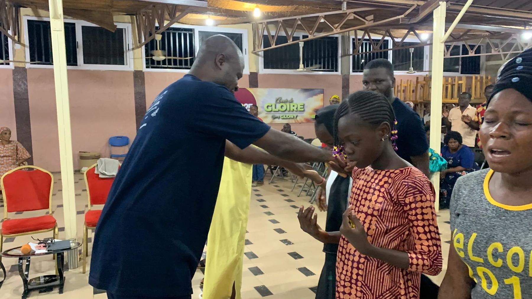 A team member praying for a girl as a woman beside her prays