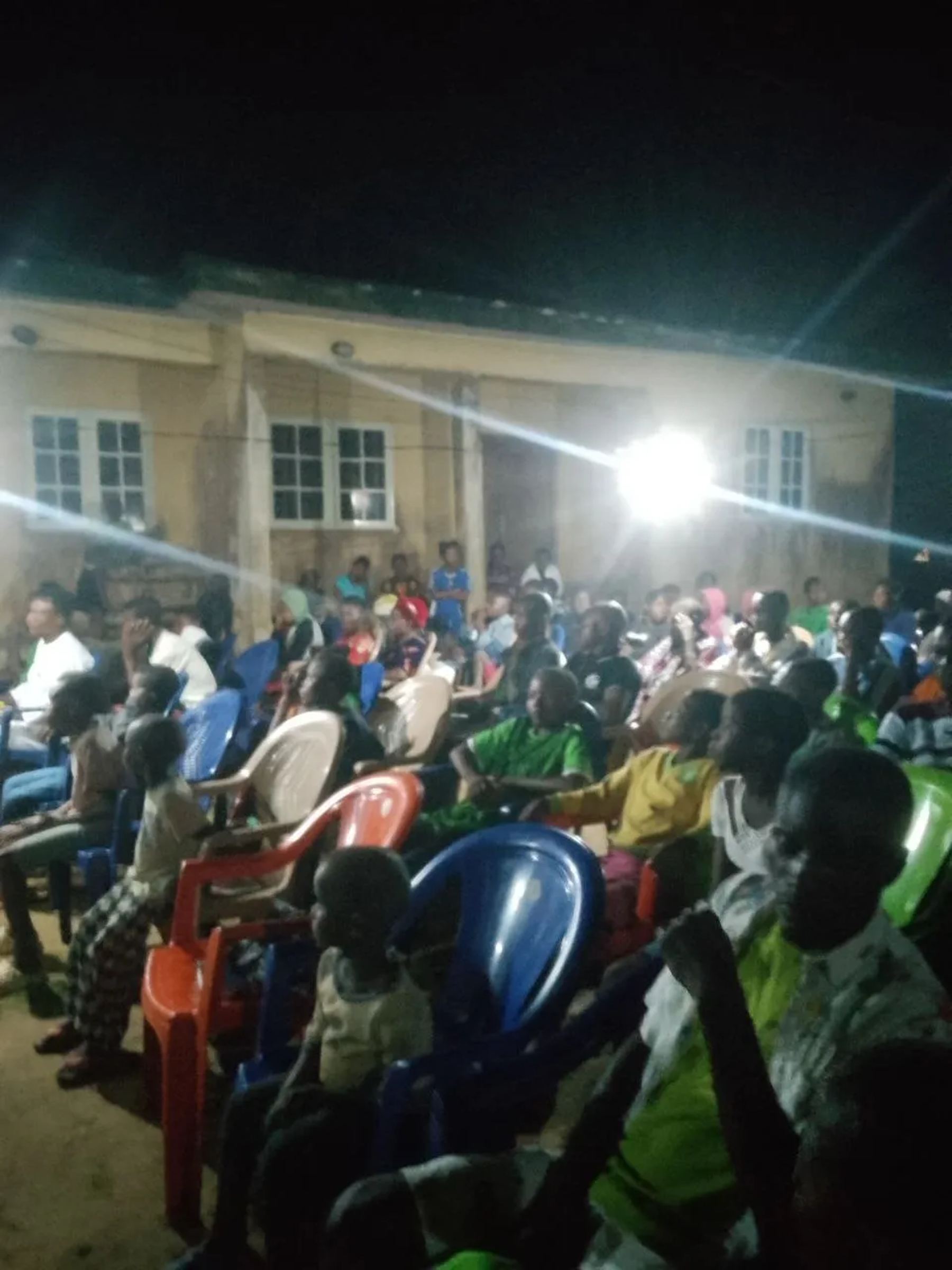 Children and adults filling the chairs at the night meeting