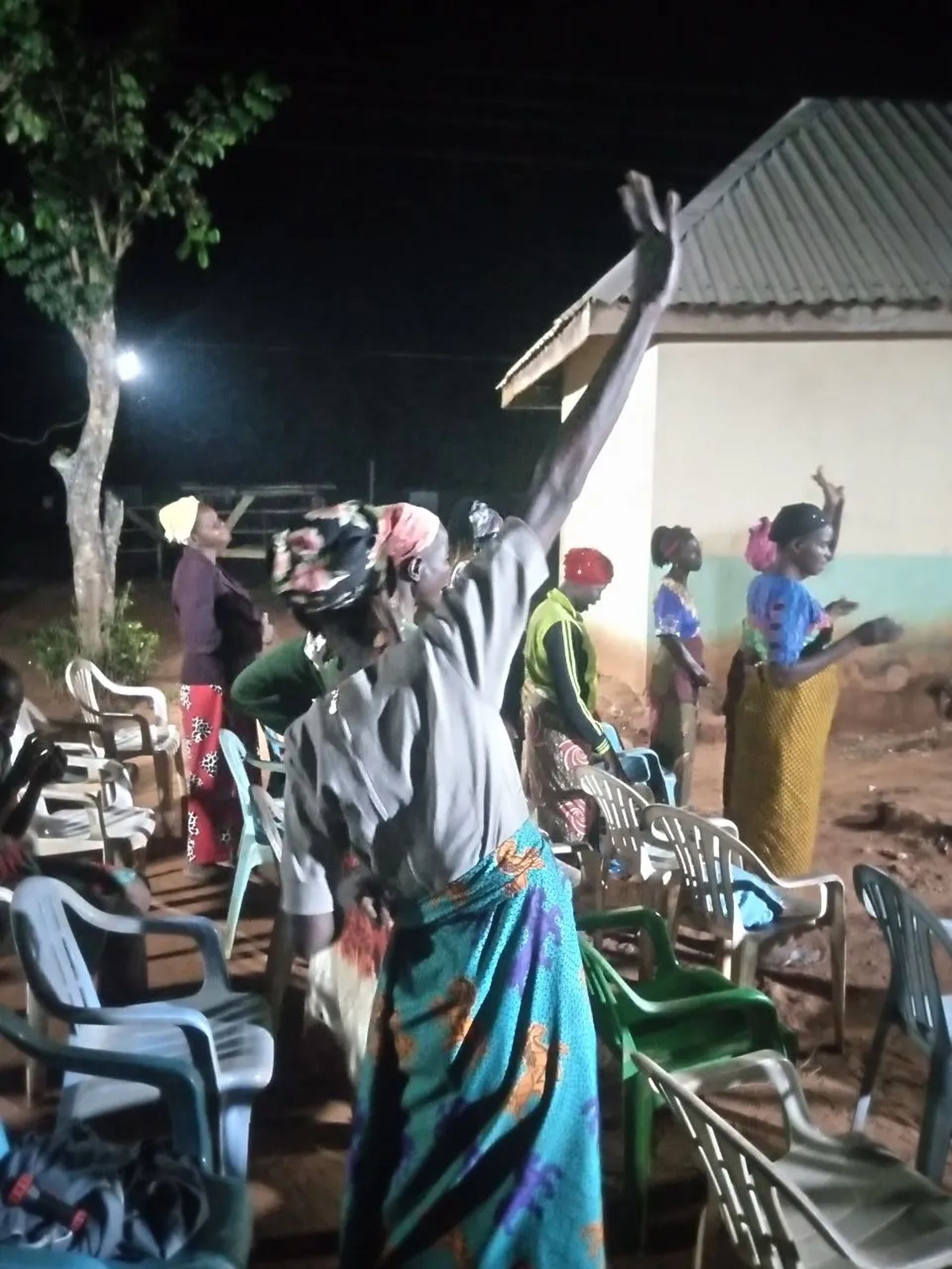 A woman with a raised arm in worship at the night outreach