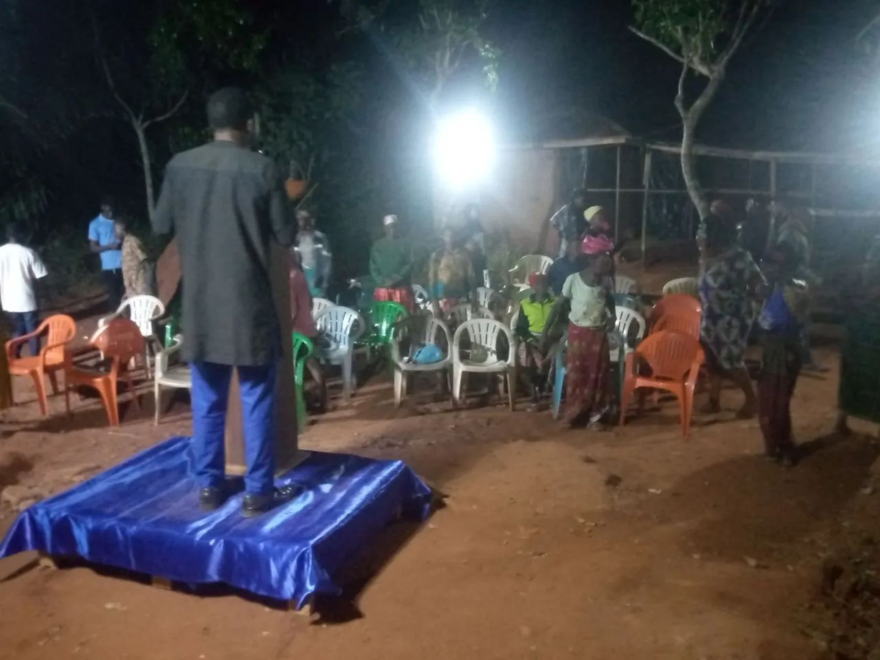 A preacher speaking from the blue platform to the crowd