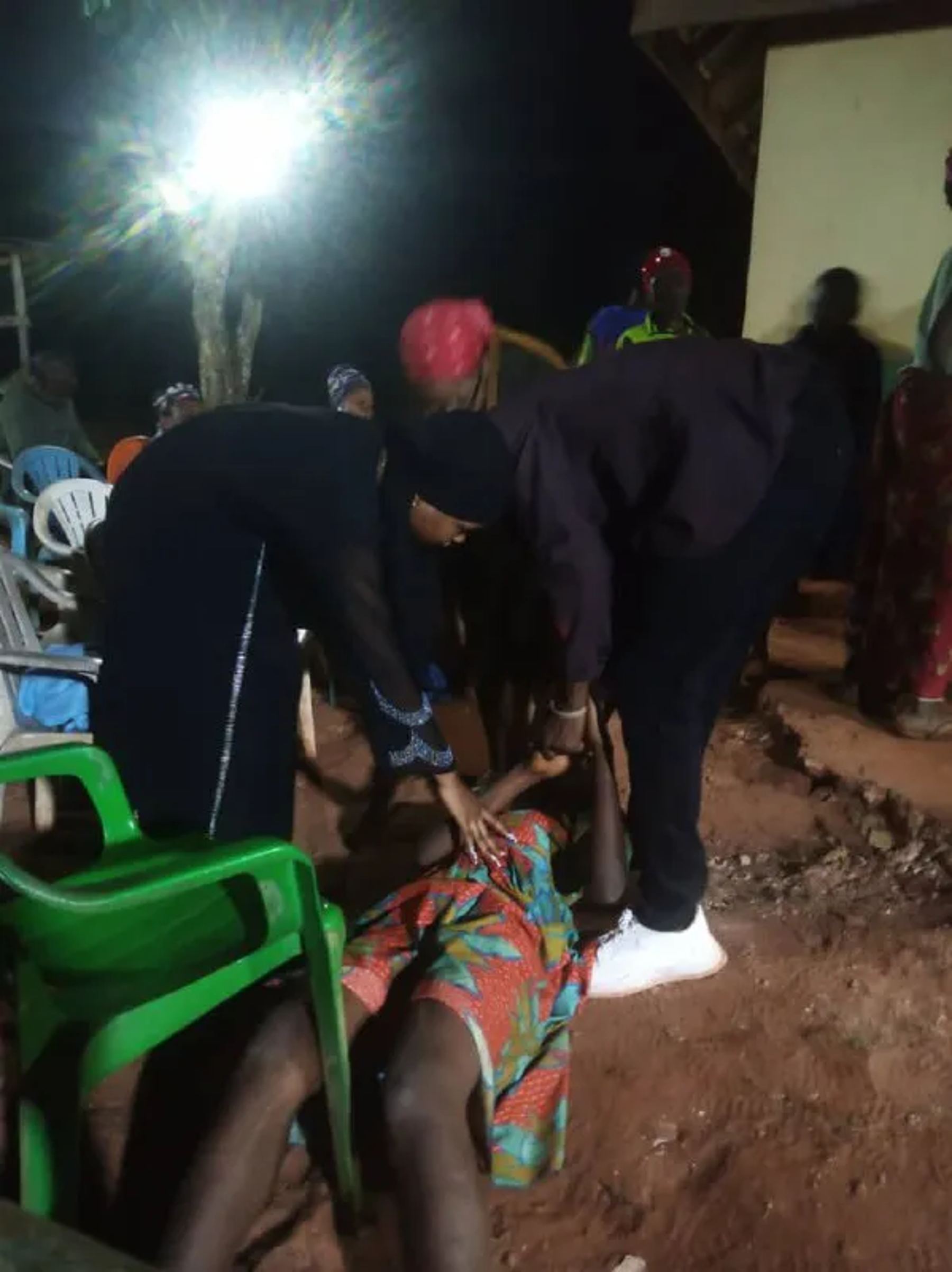 Team members praying with a woman on the ground