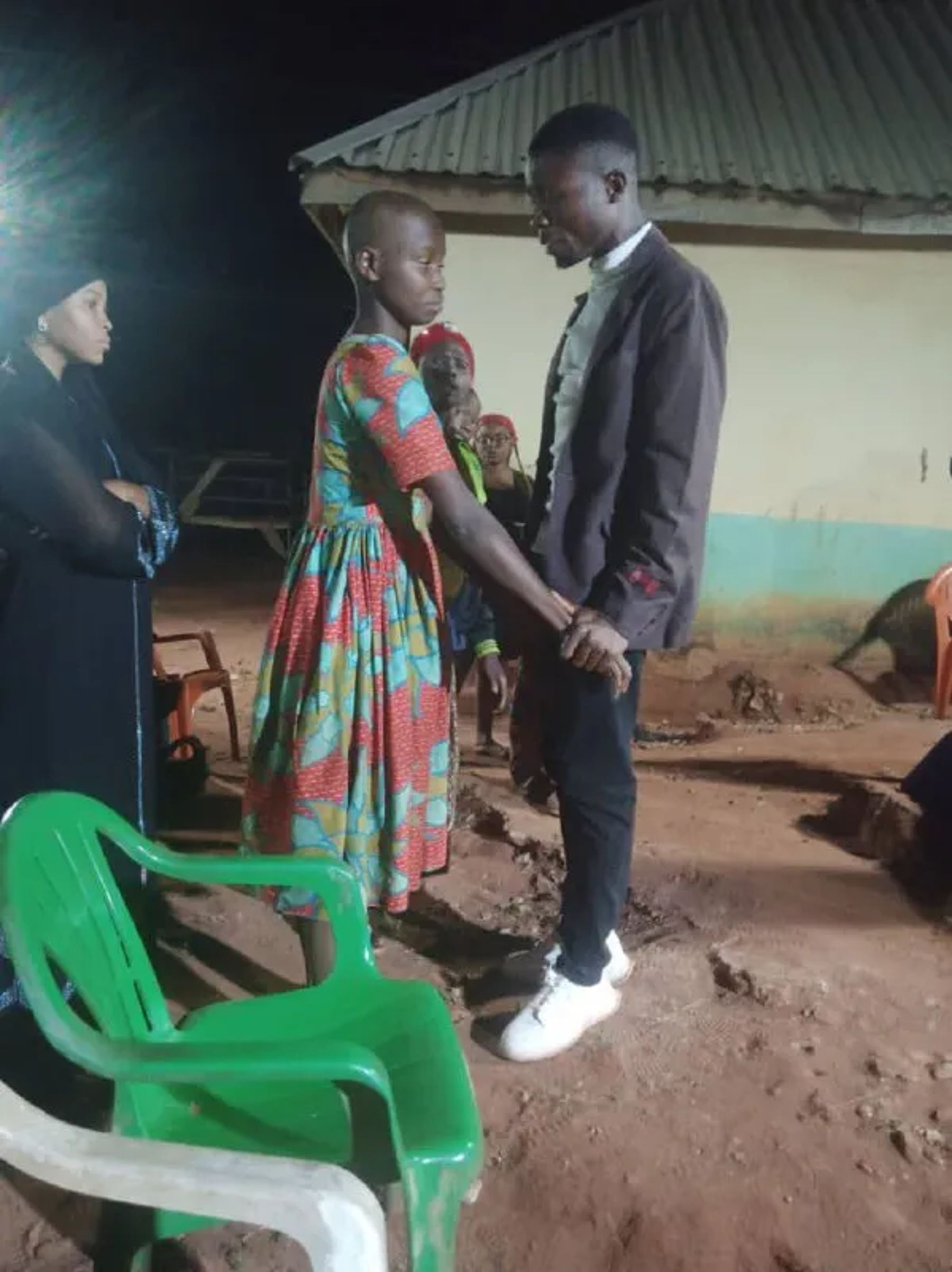 A team member praying with a woman beside the green chairs