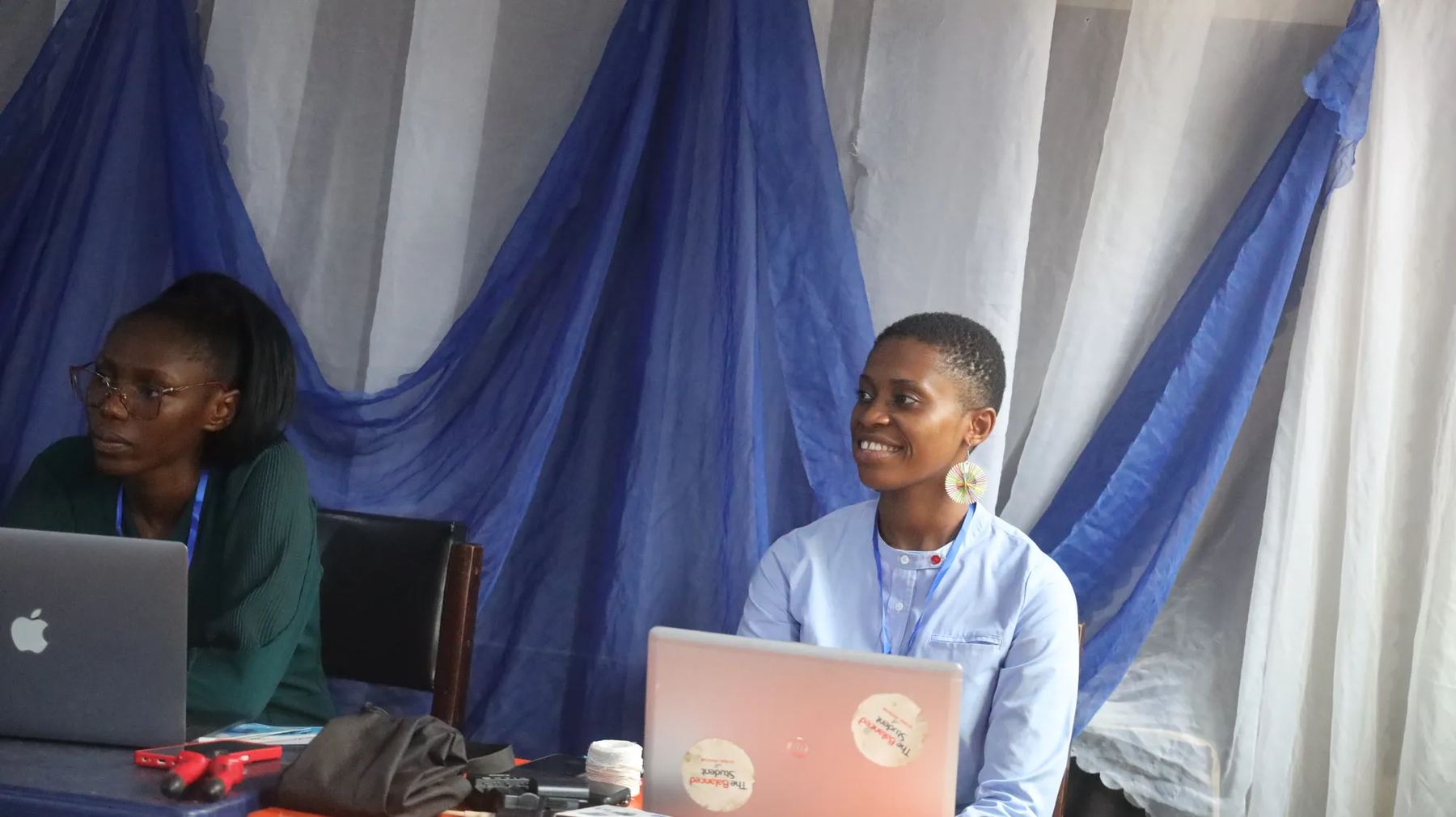 Two members of the team at their laptops beside the conference stage