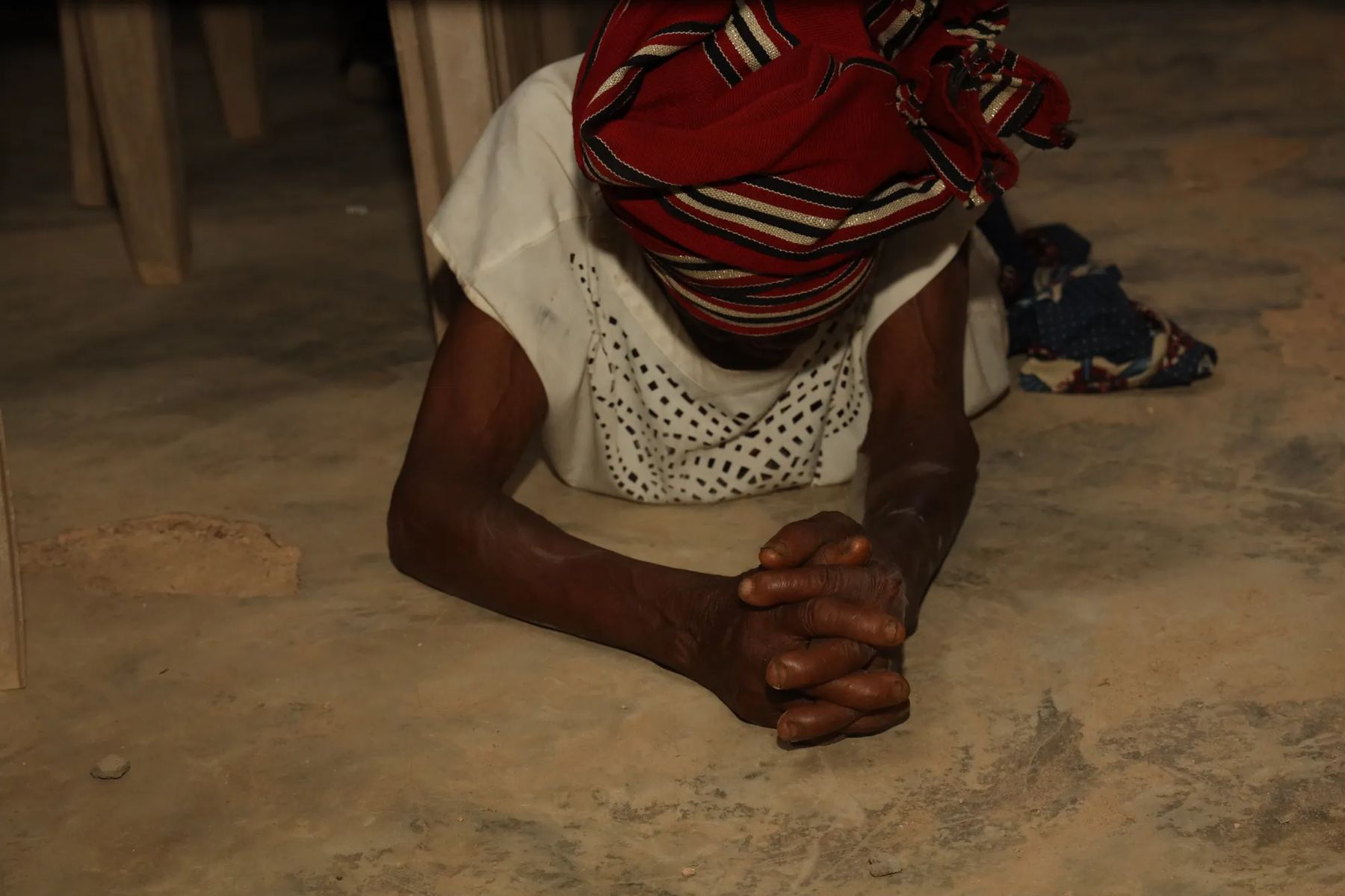 A woman kneeling with her face to the ground in prayer