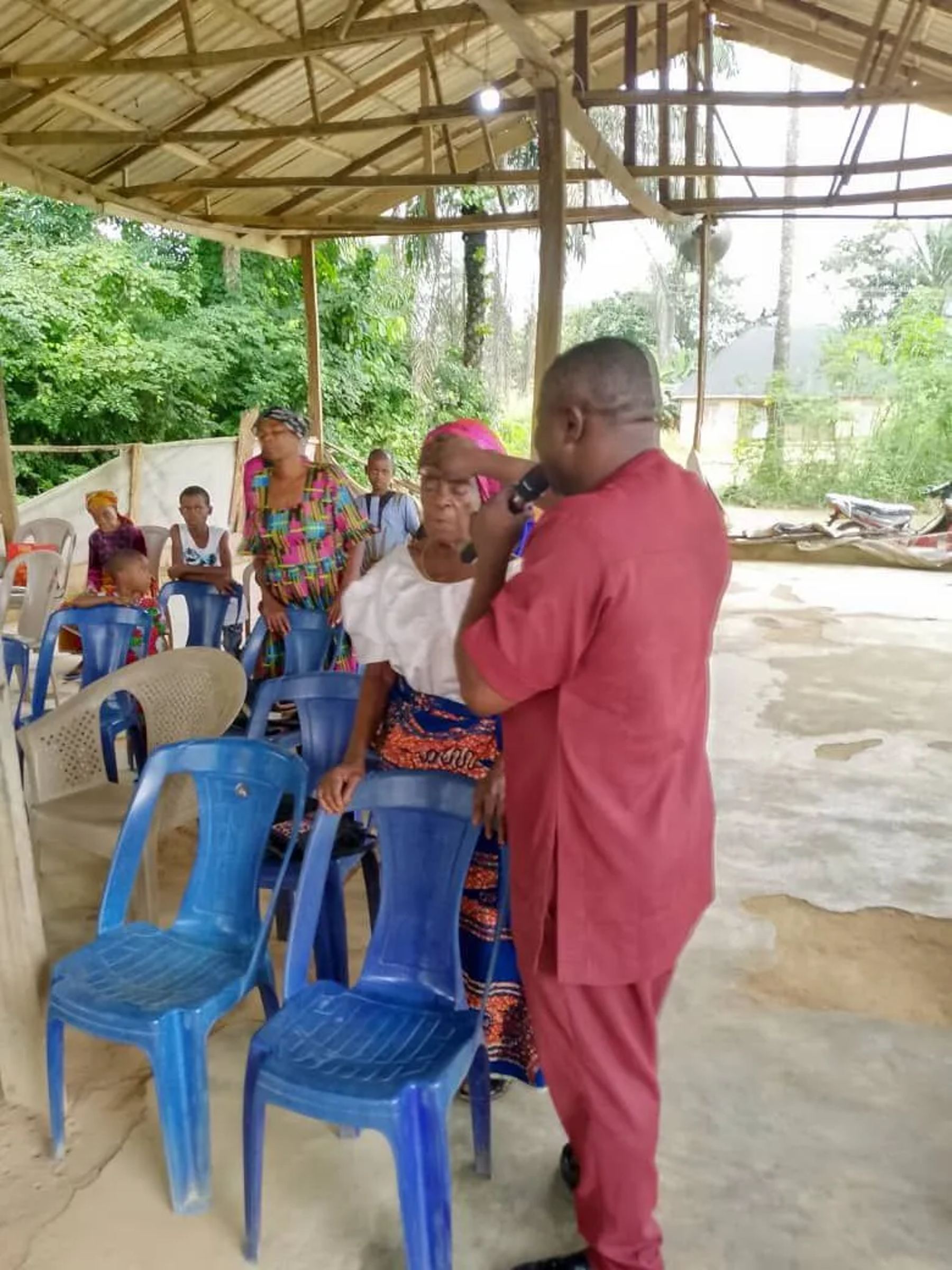 A minister with a microphone praying with a woman among the congregation