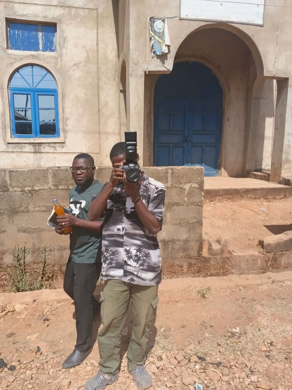 Two team members outside a building, one taking photos with a camera