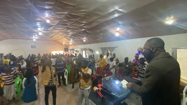 A packed church hall in worship, with the sound desk in the foreground